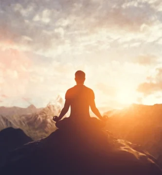 Hombre en postura de yoga meditando al atardecer con música zen ultra relajante, bienestar mental y cuidado corporal