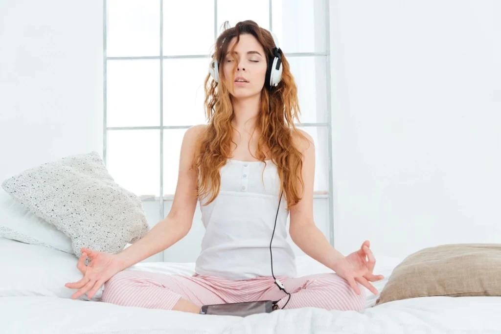 Mujer meditando en la cama con música zen